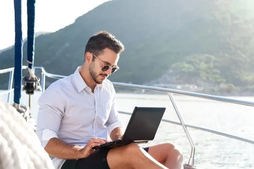 Man on a boat on a laptop - work and travel